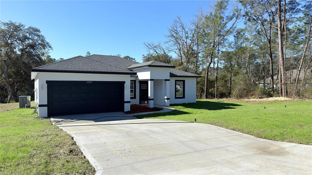 A single-story house with a white stucco exterior, dark trim, and a two-car garage — 15777 SW 55TH AVENUE ROAD, OCALA, FL
