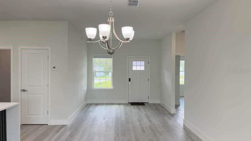 A dining area features light gray wood-look flooring, a white front door, and a chandelier — 15777 SW 55TH AVENUE ROAD, OCALA, FL
