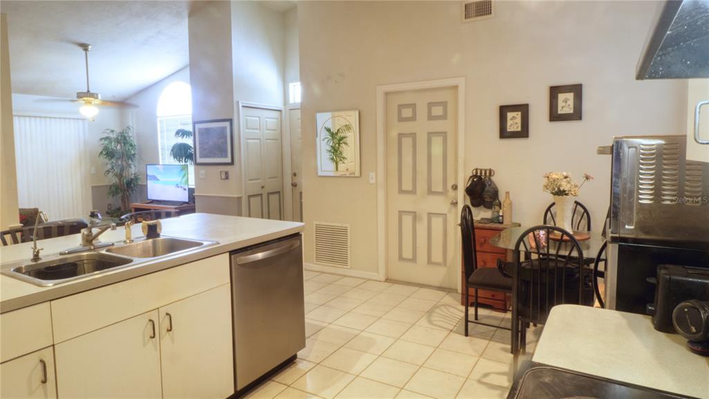 A kitchen with white cabinets, a stainless steel dishwasher, and a dining area with tile flooring — 1931 SW 73RD STREET, GAINESVILLE, FL