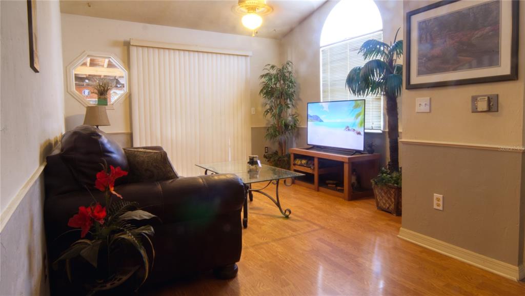 A living room features a dark leather sofa, a glass coffee table, and a television — 1931 SW 73RD STREET, GAINESVILLE, FL