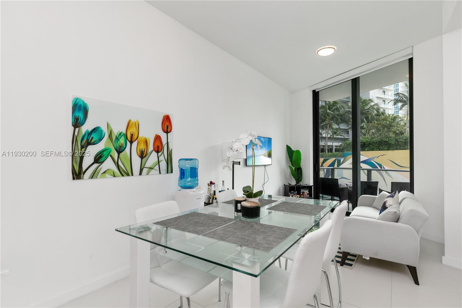 A dining area with a glass table, white chairs, and a balcony view — 501 NE 31st St # 307, Miami FL 33137, MIAMI, FL