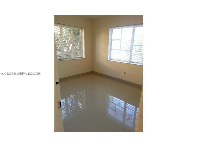 An empty room features light-colored walls, large windows with blinds, and polished tile flooring — 645 83rd St # 50, Miami Beach FL 33141, MIAMI BEACH, FL
