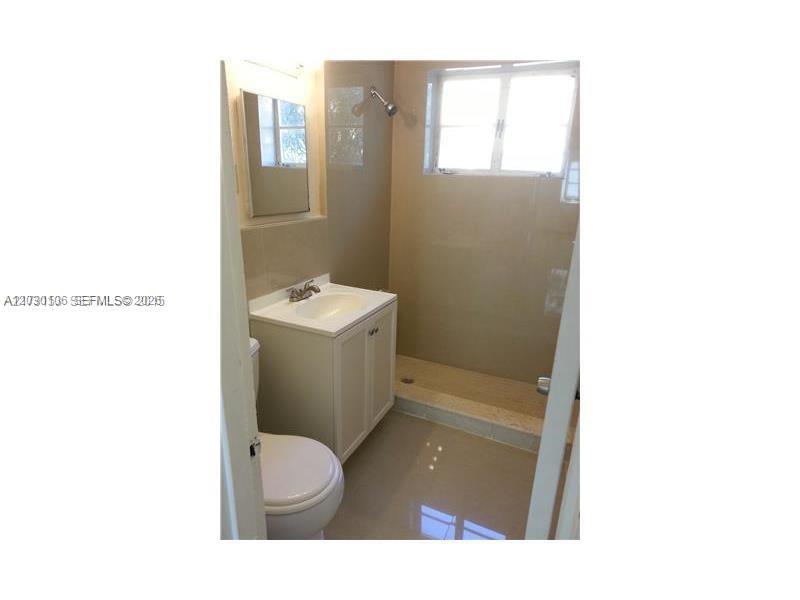 A bathroom features a white vanity, a toilet, and a walk-in shower with tiled walls — 645 83rd St # 50, Miami Beach FL 33141, MIAMI BEACH, FL