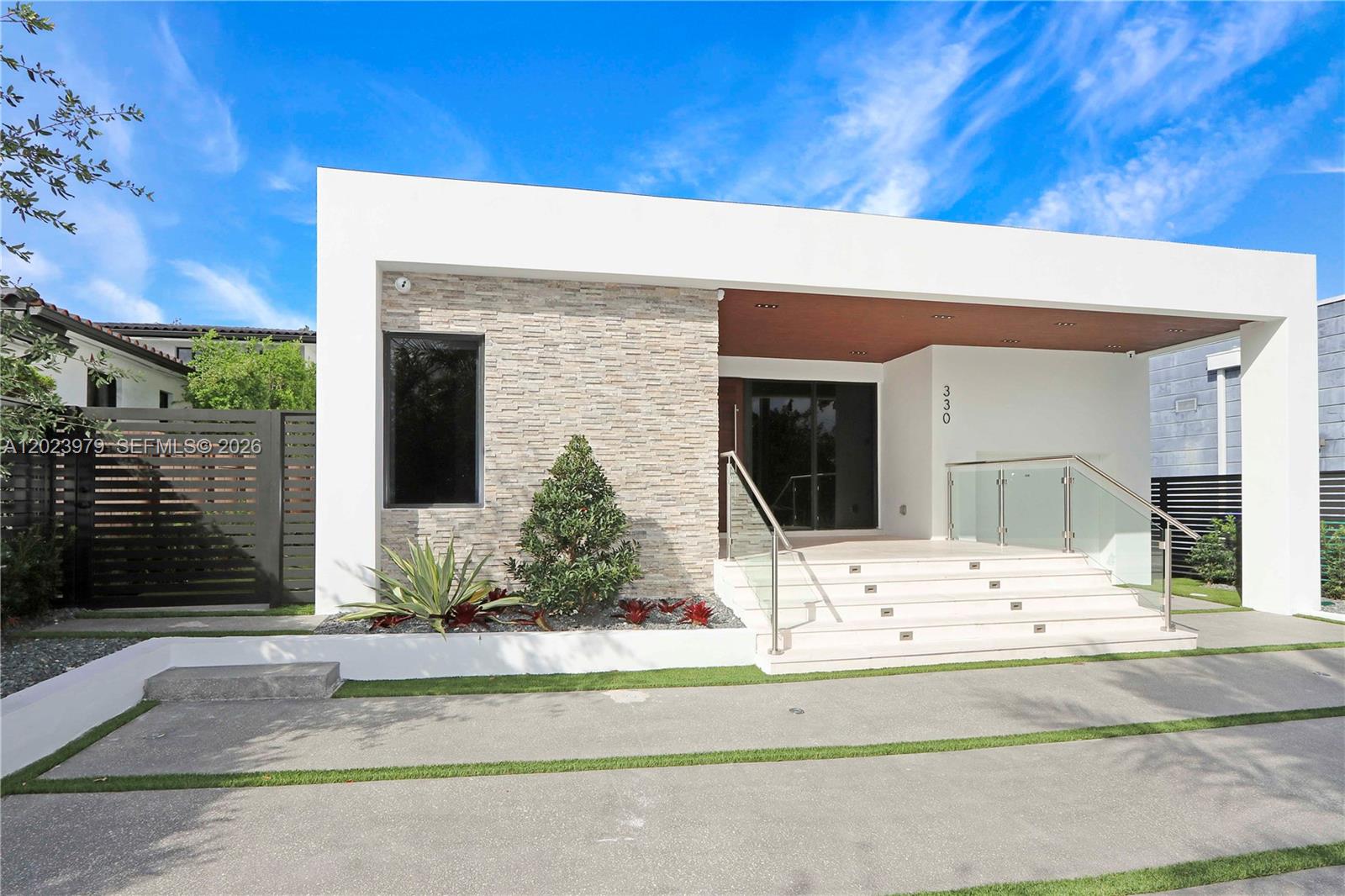 A modern house exterior features a stone facade, white frame, and a glass-railed staircase — 330 SW 19th Rd, Miami FL 33129, MIAMI, FL