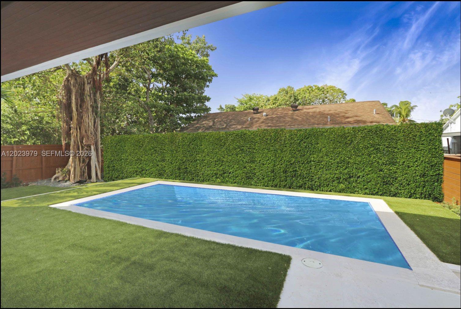 A rectangular swimming pool is surrounded by artificial turf and a tall green hedge — 330 SW 19th Rd, Miami FL 33129, MIAMI, FL