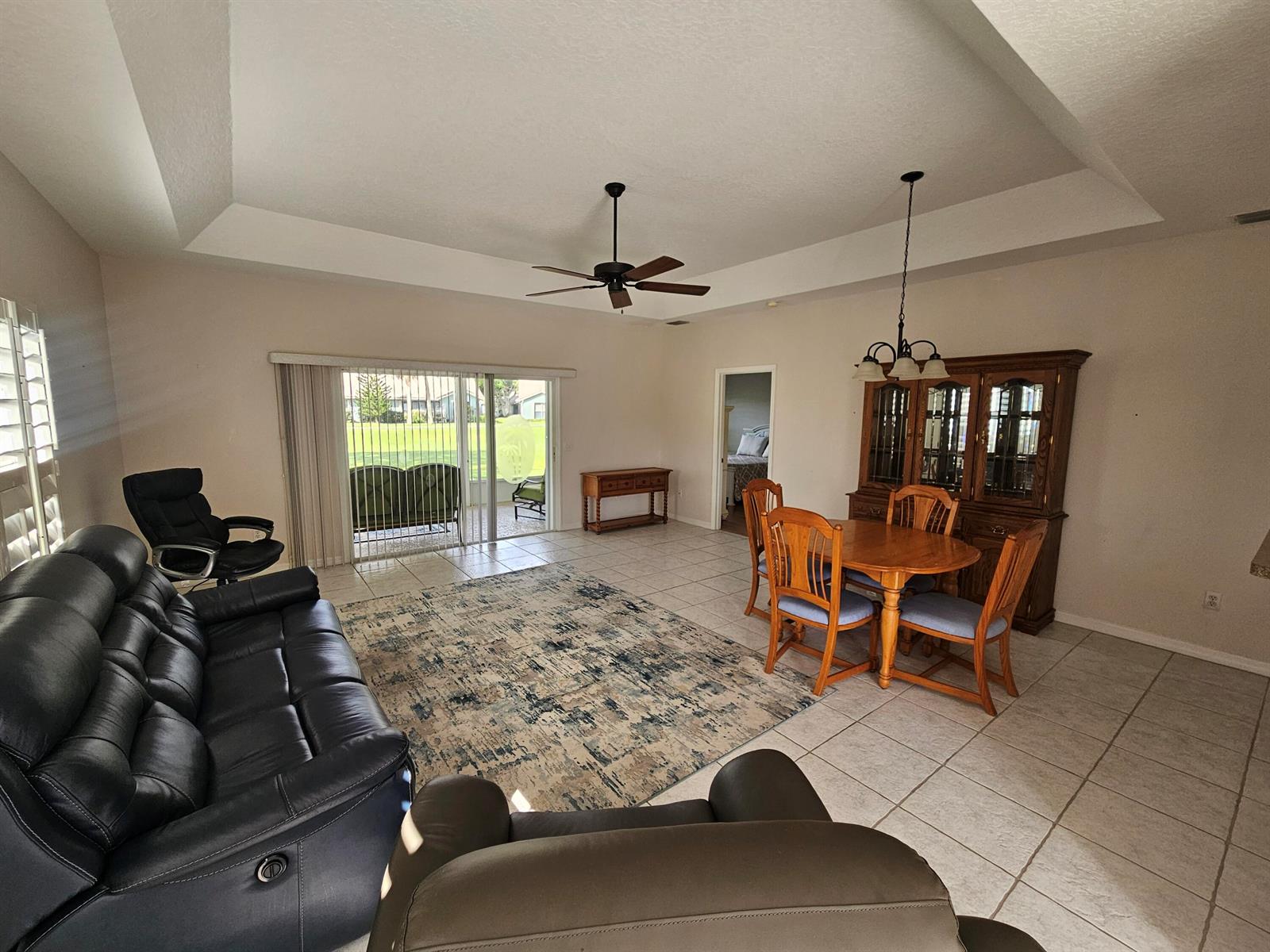 A living and dining area with tile floors, a tray ceiling, and sliding glass doors — 4011 Gator Trace Road, Fort Pierce FL 34982, FORT PIERCE, FL