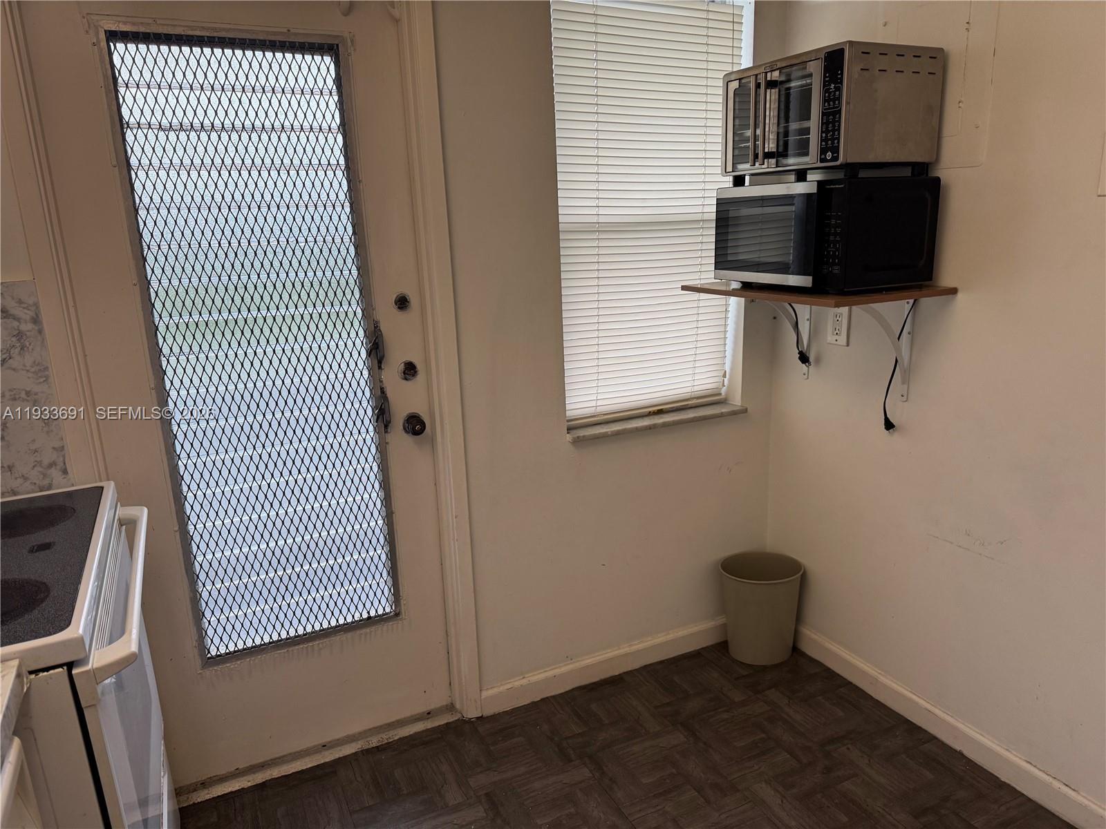 A kitchen area features a door with a security screen, a window, and appliances on a shelf — 950 Hillcrest Dr # 411, Hollywood FL 33021, HOLLYWOOD, FL