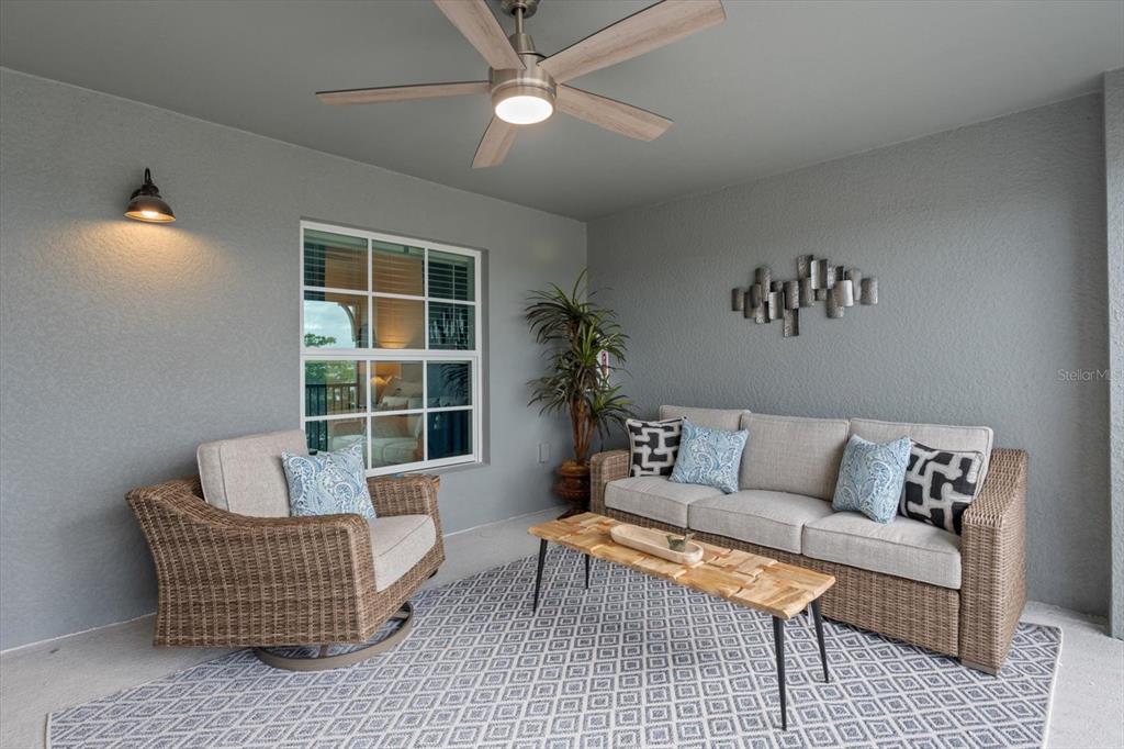 A covered patio features wicker furniture, a patterned rug, and a ceiling fan — 12440 WELLEN GOLF STREET UNIT 204, VENICE, FL