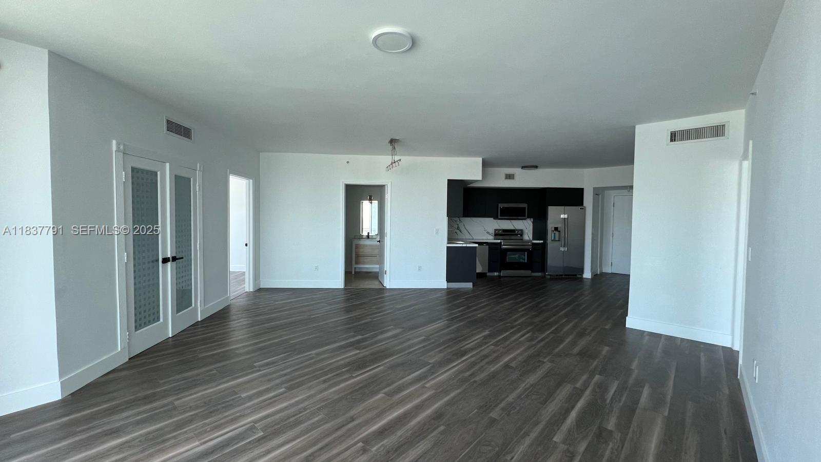 An open-concept living area features dark wood-look flooring, white walls, and a modern kitchen — 350 S Miami Ave # 2401, Miami FL 33130, MIAMI, FL