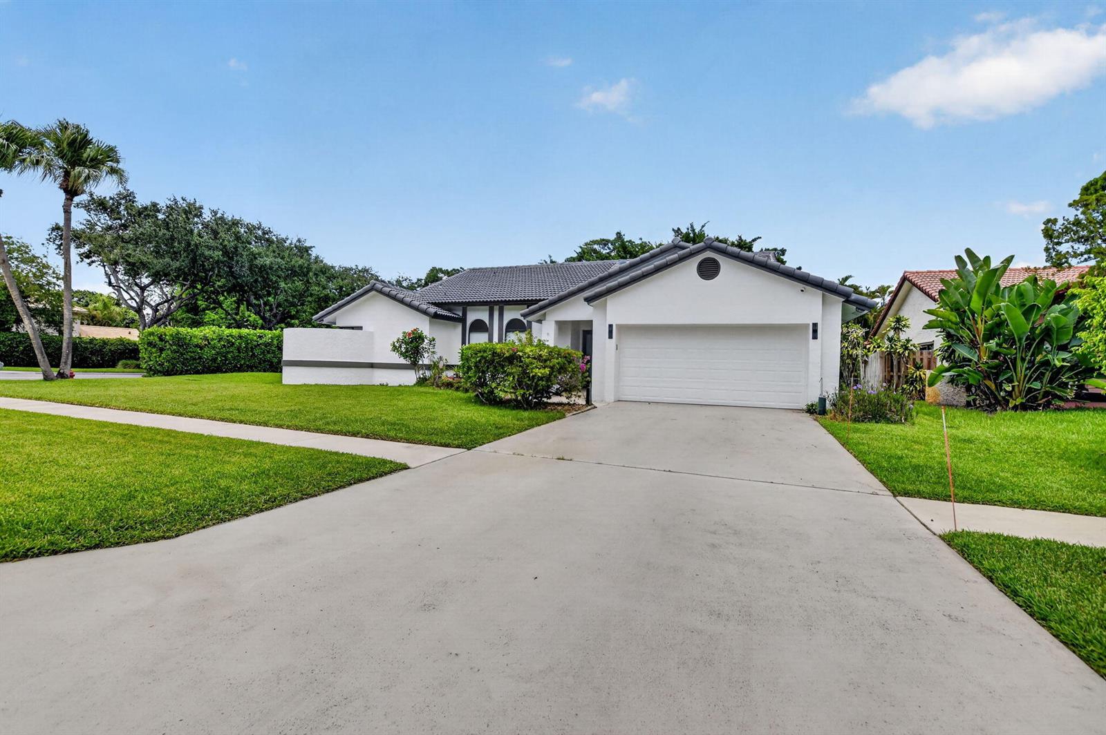 A white single-story house features a gray tiled roof and a concrete driveway — 19700 Sedgefield Terrace, Boca Raton FL 33498, BOCA RATON, FL