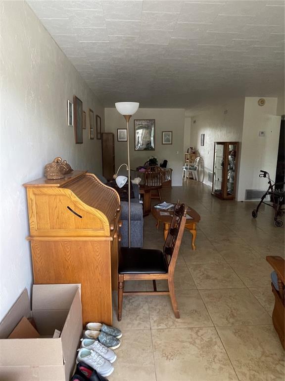 A living room features tile flooring, a wooden roll-top desk, and a dining area beyond — 4144 57TH STREET N UNIT 269, KENNETH CITY, FL