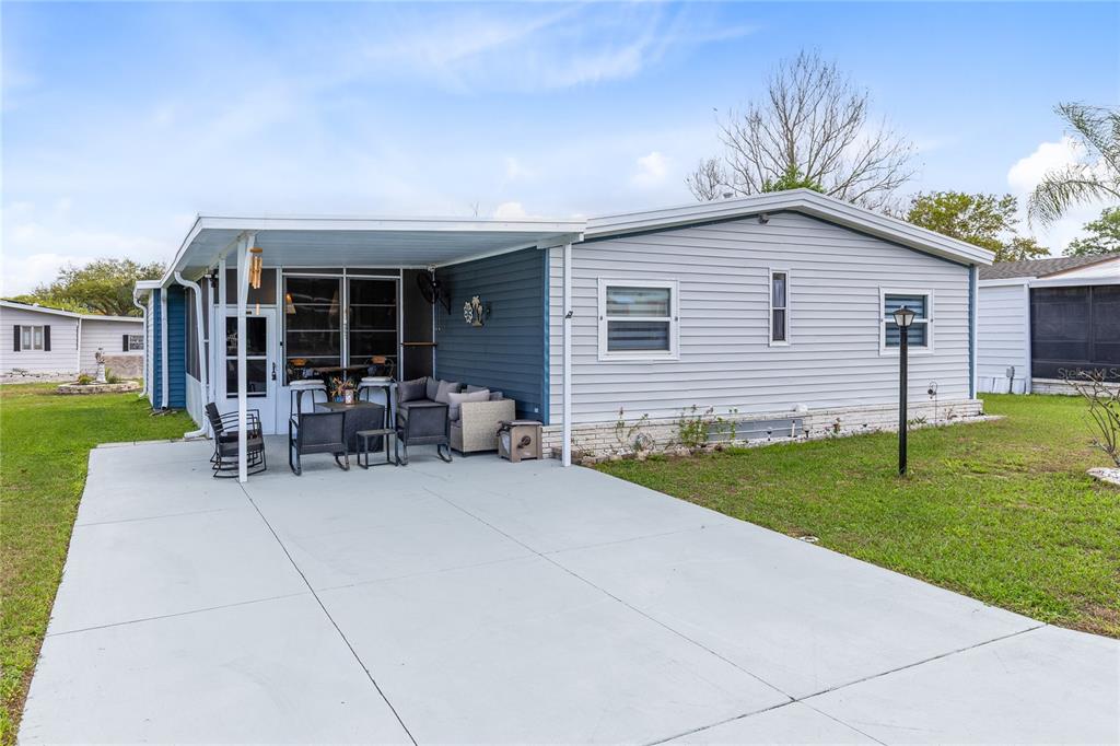 A single-story manufactured home with a concrete driveway, covered patio, and light gray siding — 516 RANGER PARK COURT, DAVENPORT, FL