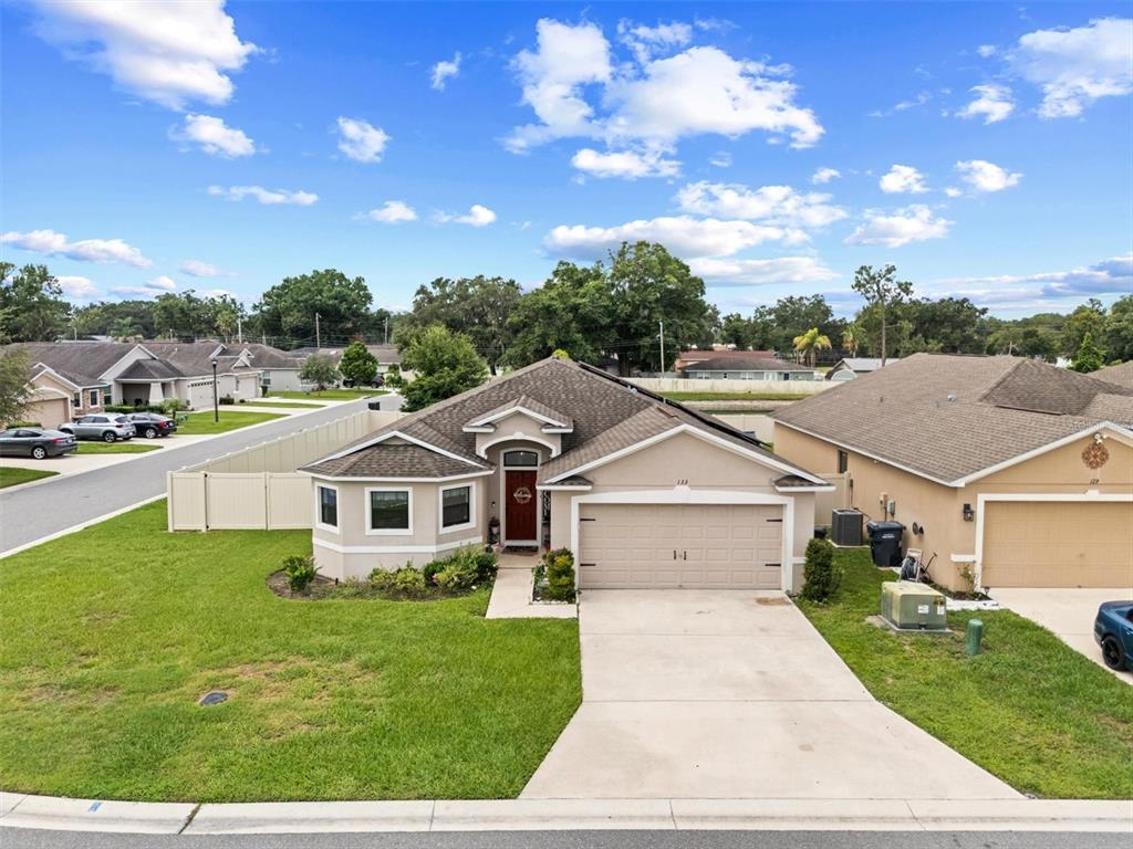 A single-story suburban house with a tan exterior, a two-car garage, and a front lawn — 133 CROSSING DRIVE, LAKELAND, FL
