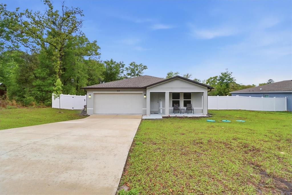 A single-story house with a two-car garage, covered porch, and white vinyl privacy fence — 10116 N ALLEGHENY WAY, CITRUS SPRINGS, FL
