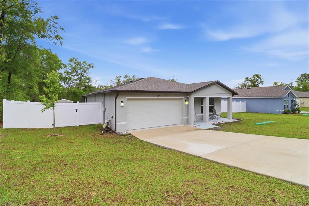 A single-story house with a white garage door, a covered porch, and a white fence — 10116 N ALLEGHENY WAY, CITRUS SPRINGS, FL