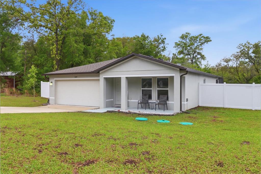 A single-story house with a two-car garage, covered front porch, and white vinyl fencing — 10116 N ALLEGHENY WAY, CITRUS SPRINGS, FL