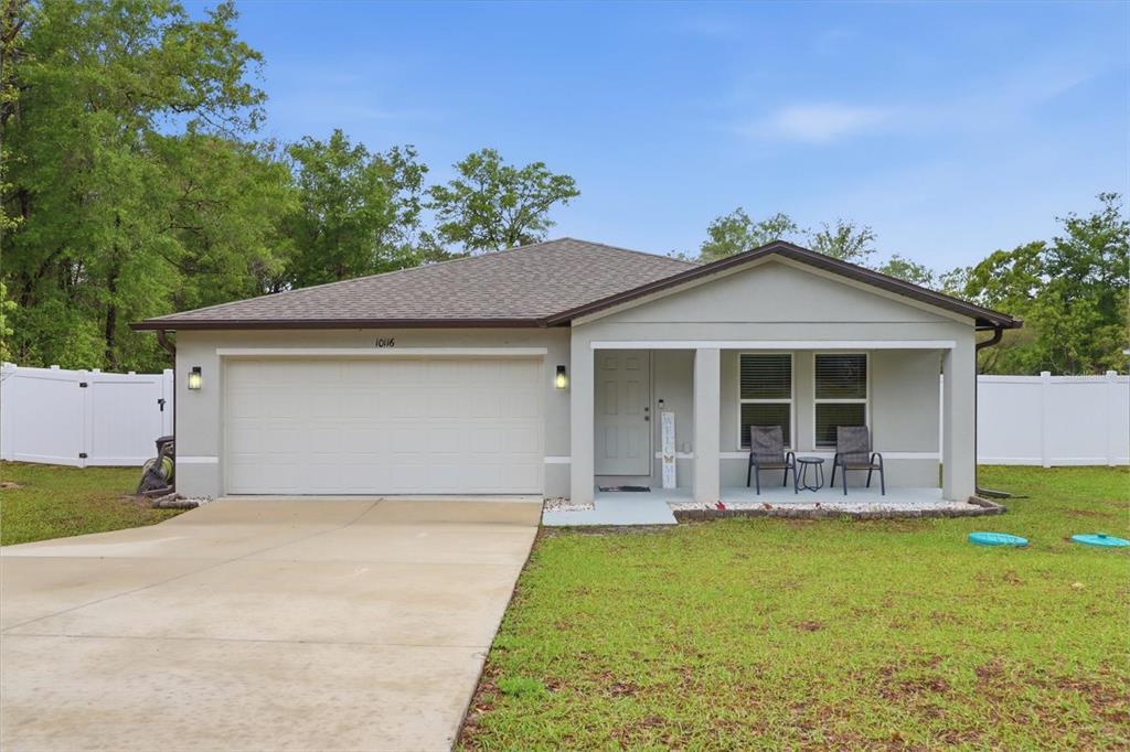 A single-story house with a two-car garage, a covered front porch, and a white fence — 10116 N ALLEGHENY WAY, CITRUS SPRINGS, FL
