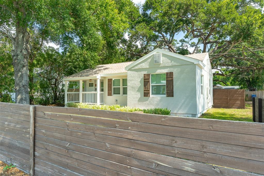 A light green single-story house with a front porch sits behind a wooden fence — 721 38TH AVENUE N, ST PETERSBURG, FL