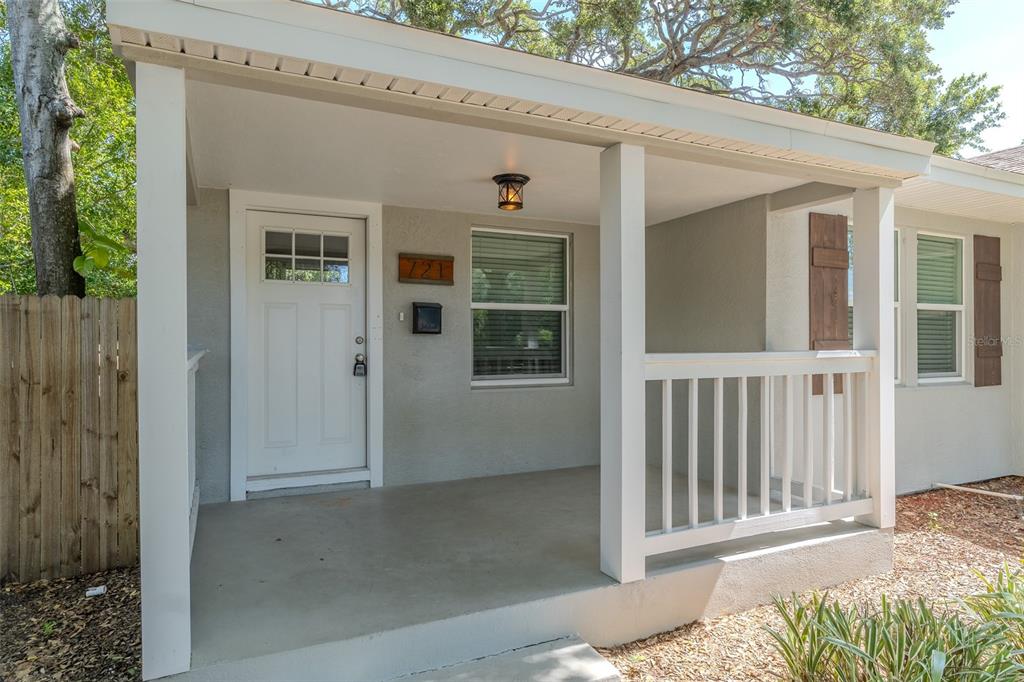A covered front porch with a white door, a window, and a wooden railing — 721 38TH AVENUE N, ST PETERSBURG, FL