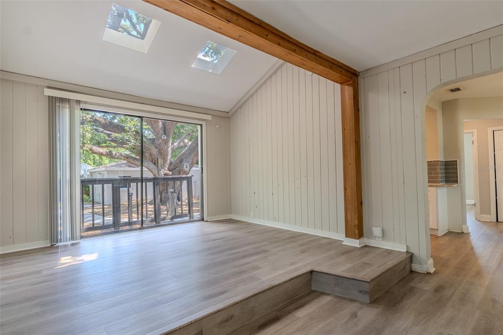 A living room with a sunken floor, wood-look flooring, skylights, and a sliding glass door — 721 38TH AVENUE N, ST PETERSBURG, FL