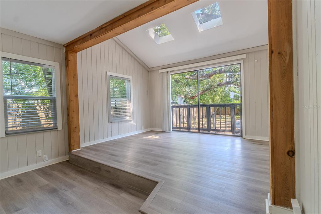 A sunroom with wood-look flooring, a sunken floor level, exposed wooden beams, and skylights — 721 38TH AVENUE N, ST PETERSBURG, FL