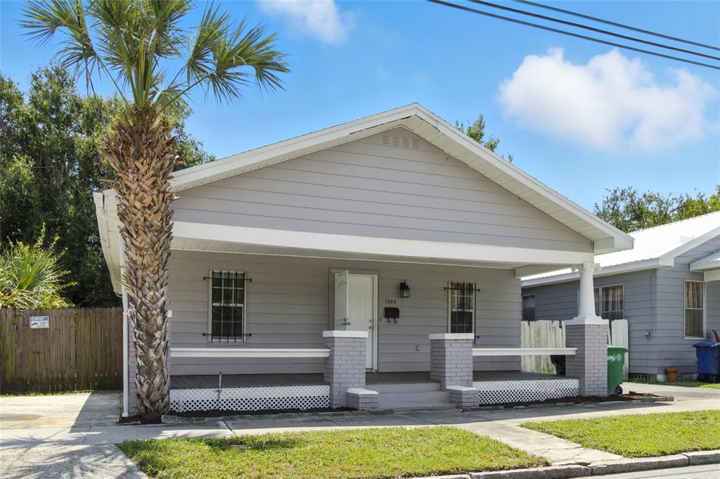 A single-story gray house with a front porch, brick pillars, and a palm tree — 1303 E 26TH AVENUE, TAMPA, FL