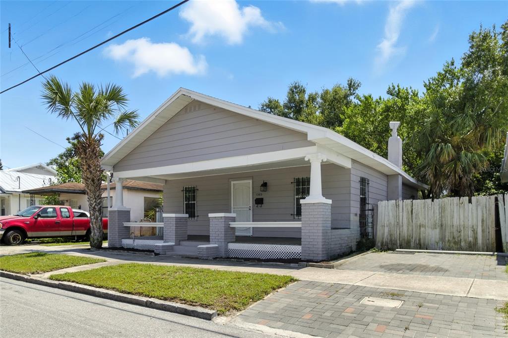 A single-story gray house with a front porch and brick pillars sits on a street — 1303 E 26TH AVENUE, TAMPA, FL