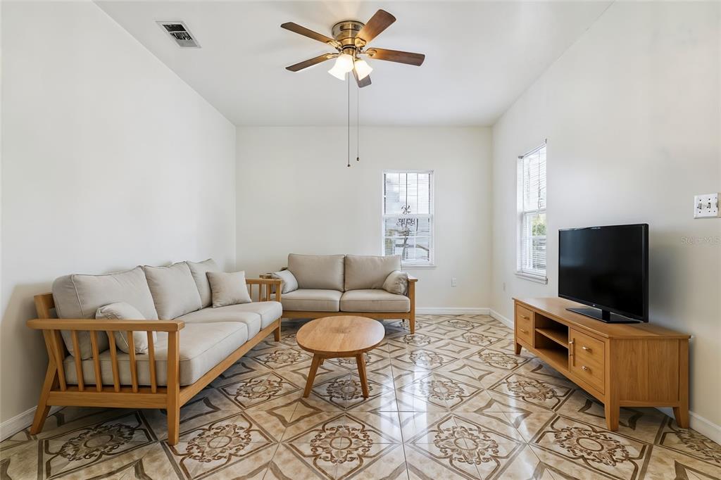A living room features light wood furniture, beige sofas, and patterned tile flooring — 1303 E 26TH AVENUE, TAMPA, FL