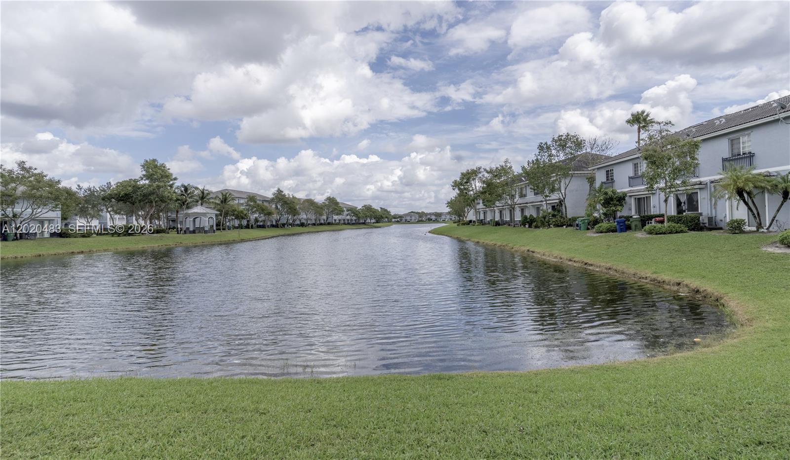 A calm lake sits between rows of multi-story residential buildings and green lawns — 1415 NW 34th Way, Lauderhill FL 33311, LAUDERHILL, FL