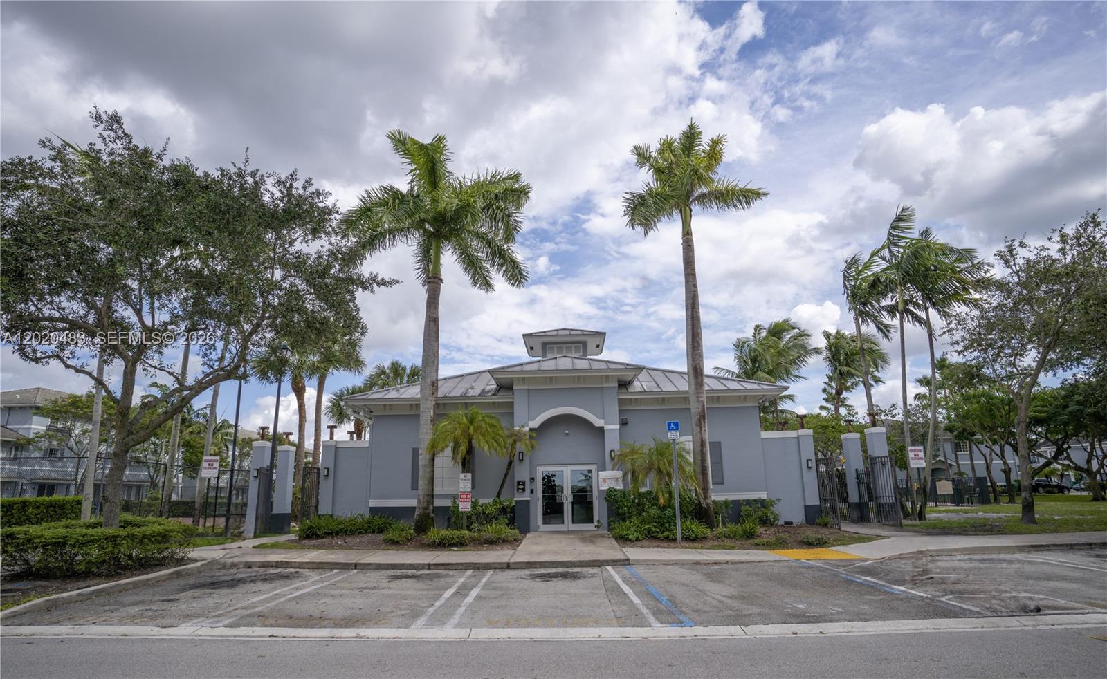 A gray, single-story building with a central entrance is framed by palm trees and parking — 1415 NW 34th Way, Lauderhill FL 33311, LAUDERHILL, FL