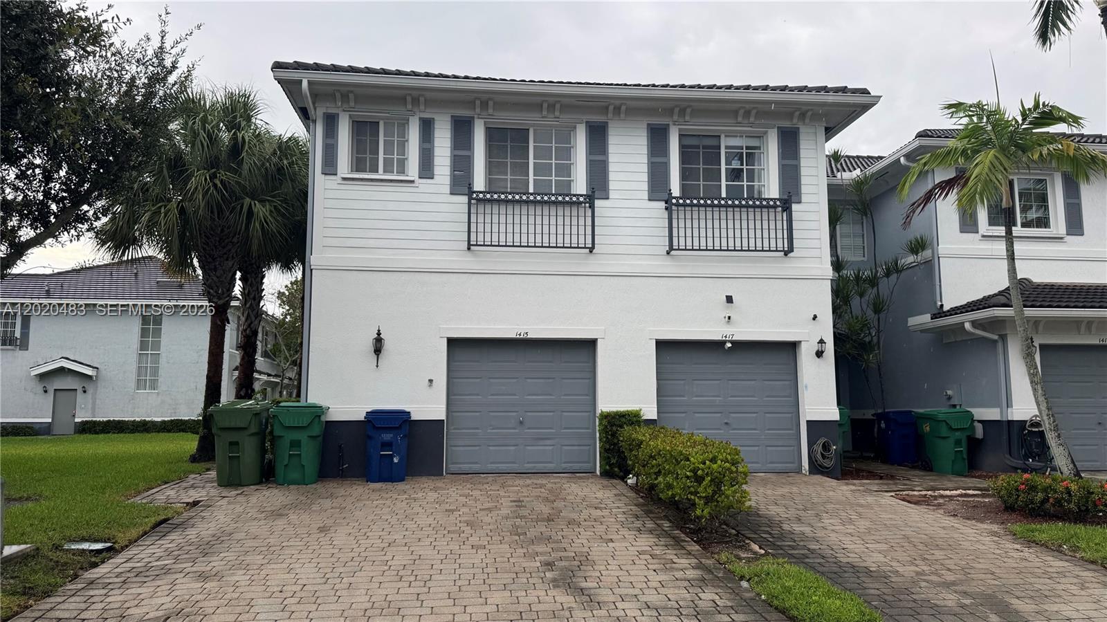 A two-story duplex features white siding, two gray garage doors, and a paved driveway — 1415 NW 34th Way, Lauderhill FL 33311, LAUDERHILL, FL