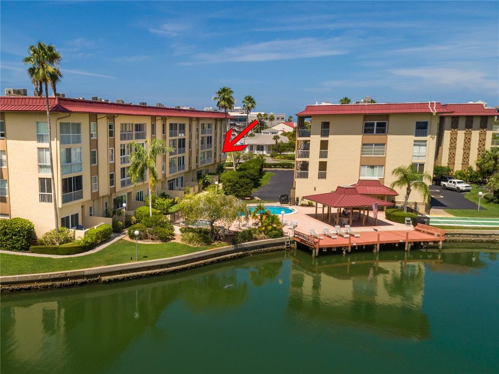 An aerial view of a waterfront apartment complex with a pool, dock, and red roofs — 105 ISLAND WAY UNIT 131, CLEARWATER BEACH, FL