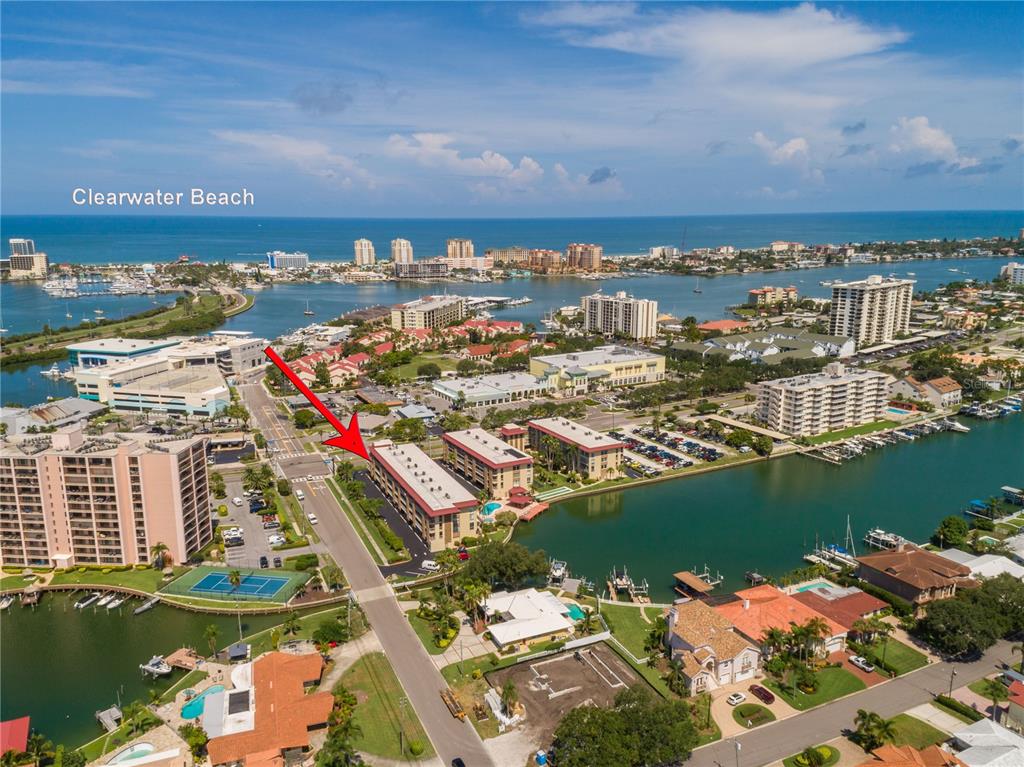 An aerial view shows a multi-story apartment building with a red arrow pointing toward it — 105 ISLAND WAY UNIT 131, CLEARWATER BEACH, FL