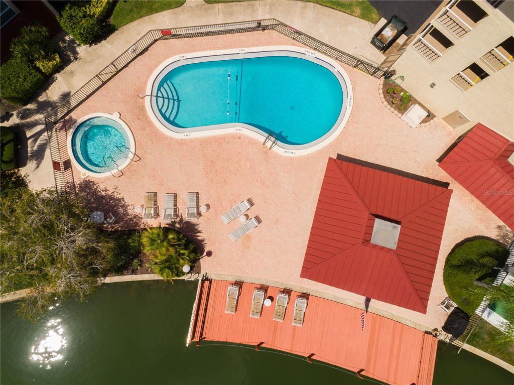An aerial view shows a swimming pool, hot tub, patio area, and a wooden dock — 105 ISLAND WAY UNIT 131, CLEARWATER BEACH, FL