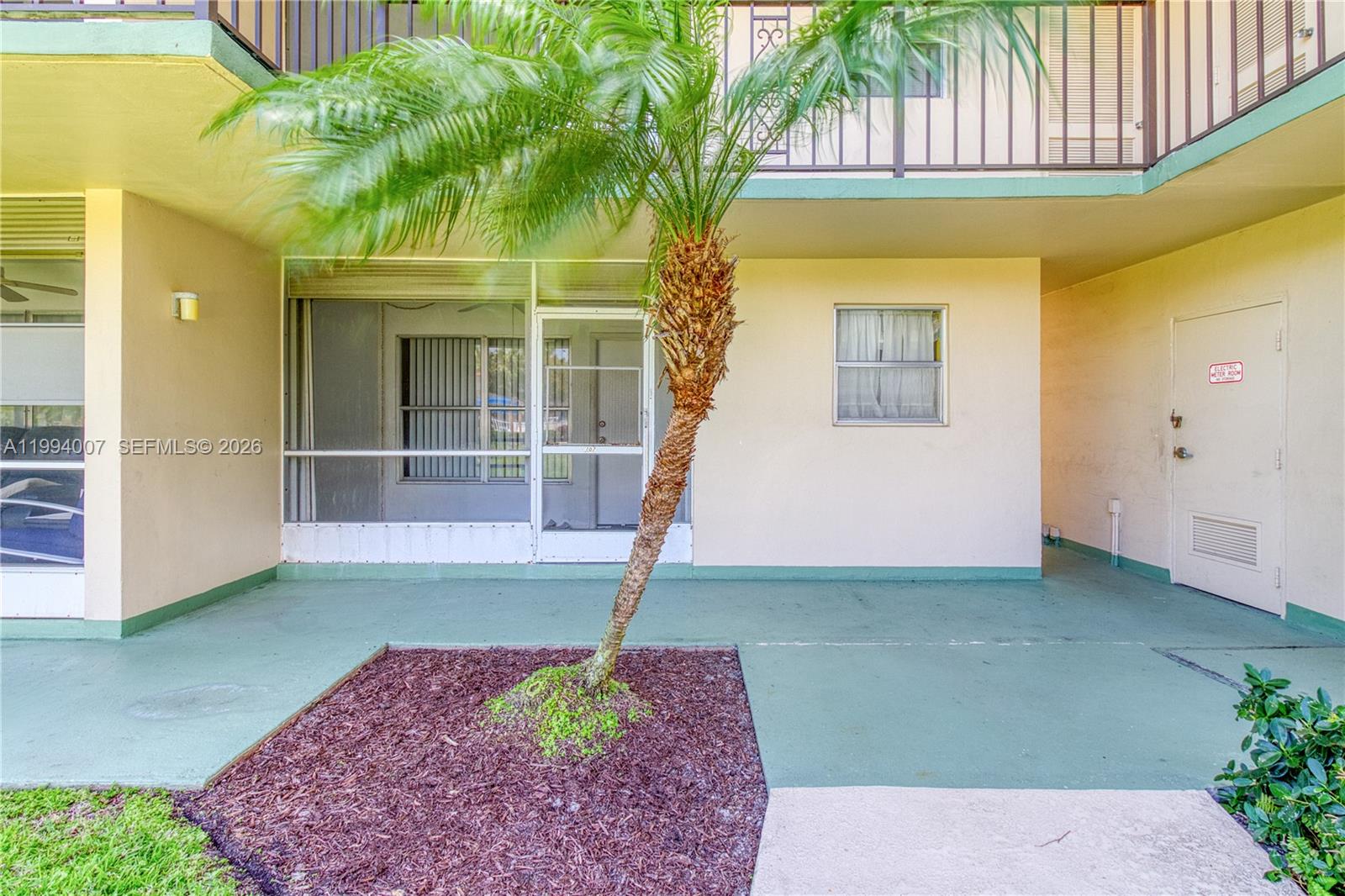 A multi-story apartment building with balconies overlooks a grassy courtyard with tropical landscaping — 804 SE 7th St # 107, Deerfield Beach FL 33441, DEERFIELD BEACH, FL