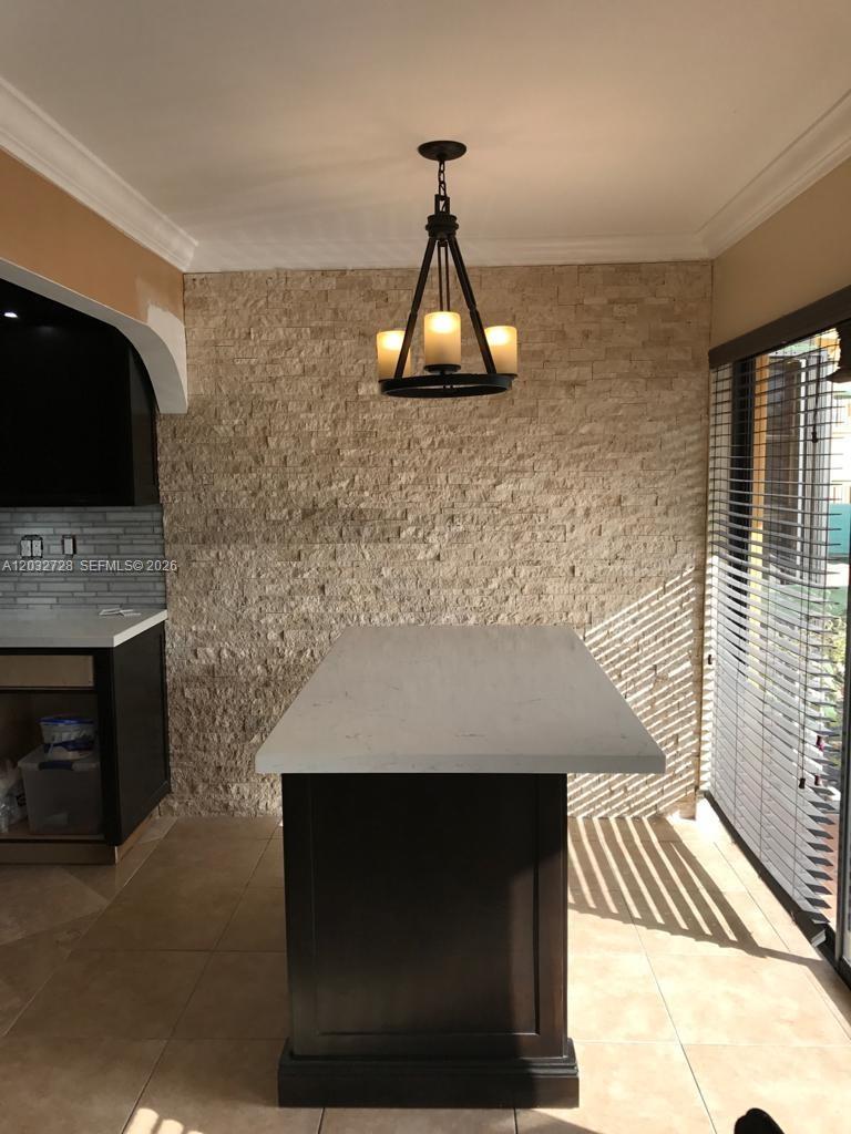 A kitchen island with a white countertop sits before a textured stone accent wall — 1300 SW 122nd Ave # 2, Miami FL 33184, MIAMI, FL