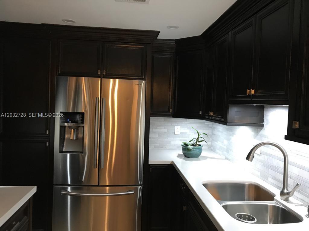 A kitchen features dark wood cabinets, stainless steel appliances, white countertops, and a tile backsplash — 1300 SW 122nd Ave # 2, Miami FL 33184, MIAMI, FL