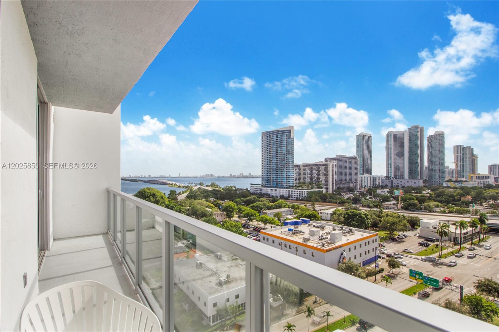 A balcony with a glass railing overlooks a city skyline, a bay, and a bridge — 3900 Biscayne Blvd # 1110, Miami FL 33137, MIAMI, FL