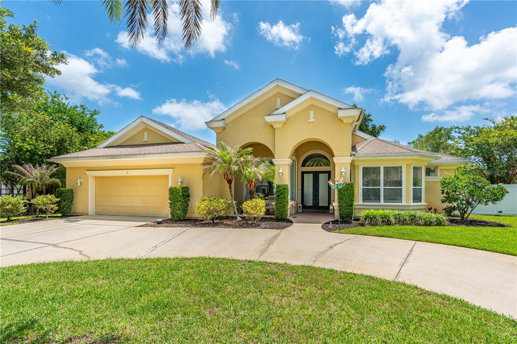A yellow single-story house with a two-car garage and a curved concrete driveway — 15 DEEP WOODS WAY, ORMOND BEACH, FL