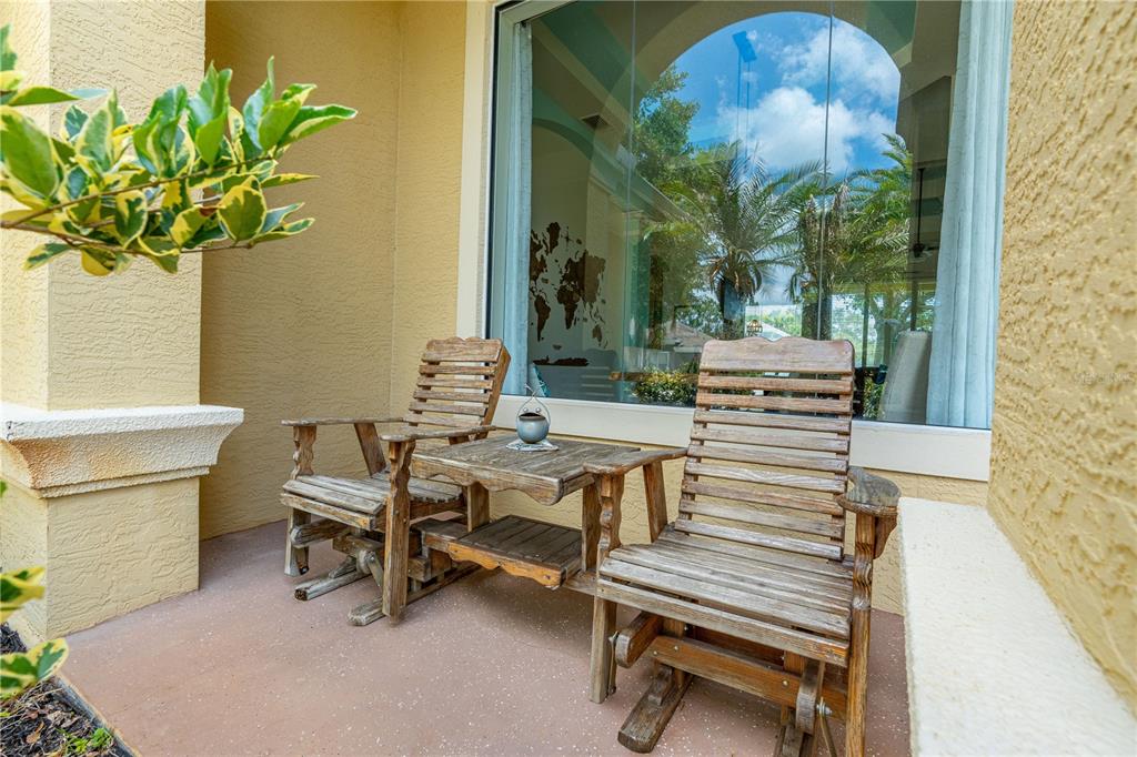 A patio features two wooden rocking chairs and a small table against a large window — 15 DEEP WOODS WAY, ORMOND BEACH, FL