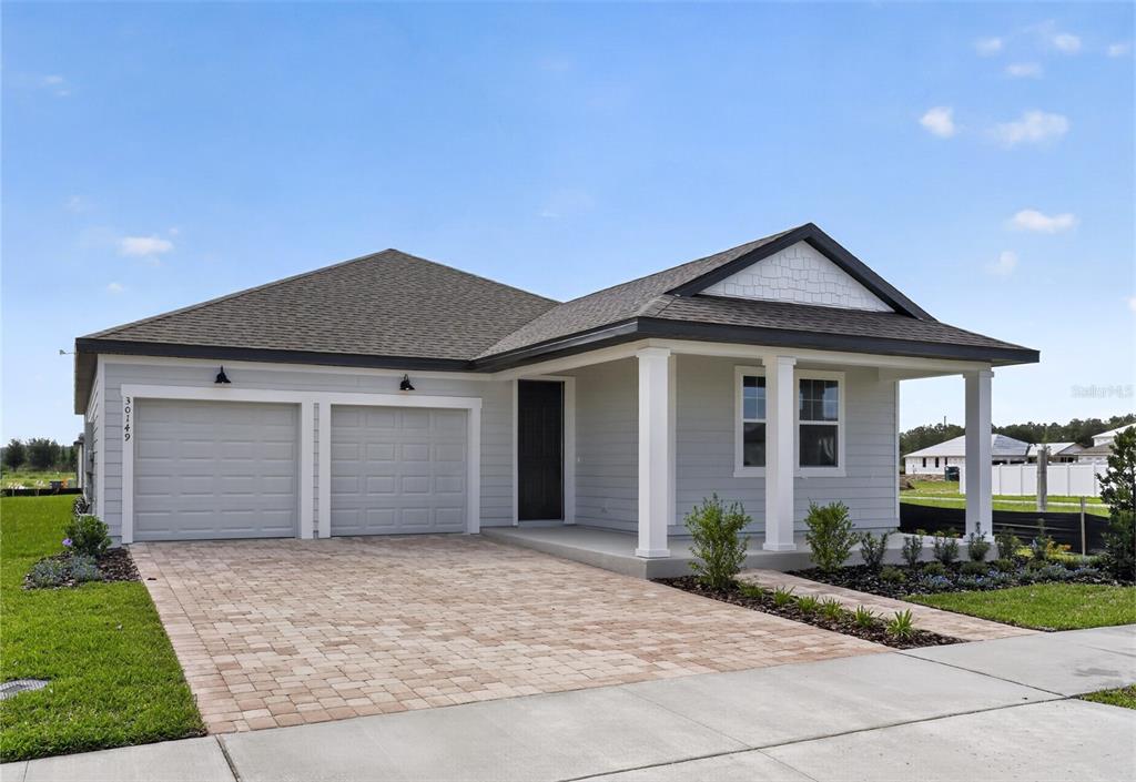 A single-story house with a two-car garage, light gray siding, and a paved driveway — 30149 MISTY PINES ROAD, MOUNT DORA, FL