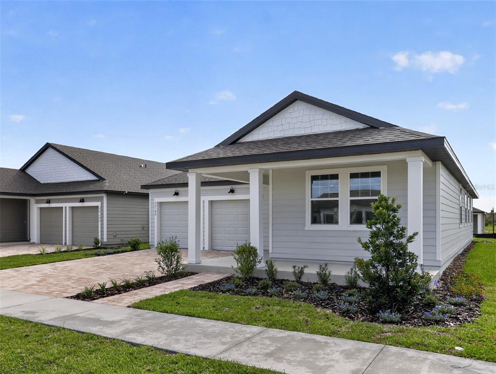 A light gray single-story house with a front porch, garage, and landscaped yard — 30149 MISTY PINES ROAD, MOUNT DORA, FL