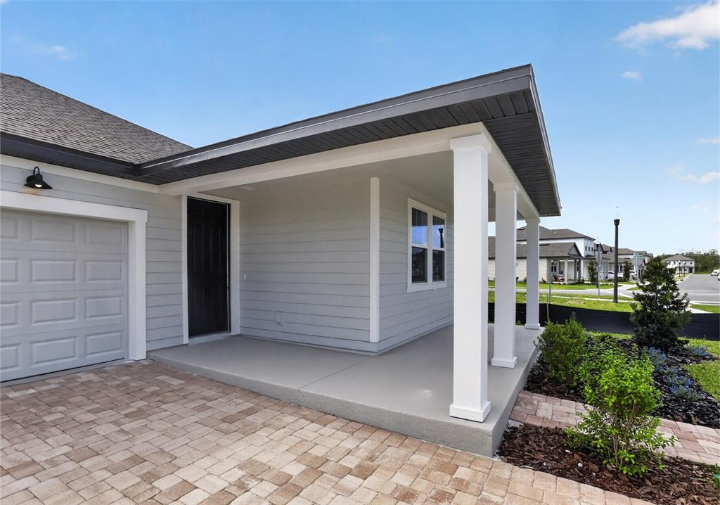 A light gray house exterior features a covered front porch, white columns, and paver driveway — 30149 MISTY PINES ROAD, MOUNT DORA, FL