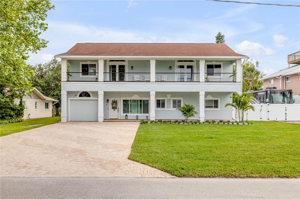 A two-story light blue house with a paved driveway, a garage, and a second-floor balcony — 90 CUNNINGHAM DRIVE, NEW SMYRNA BEACH, FL