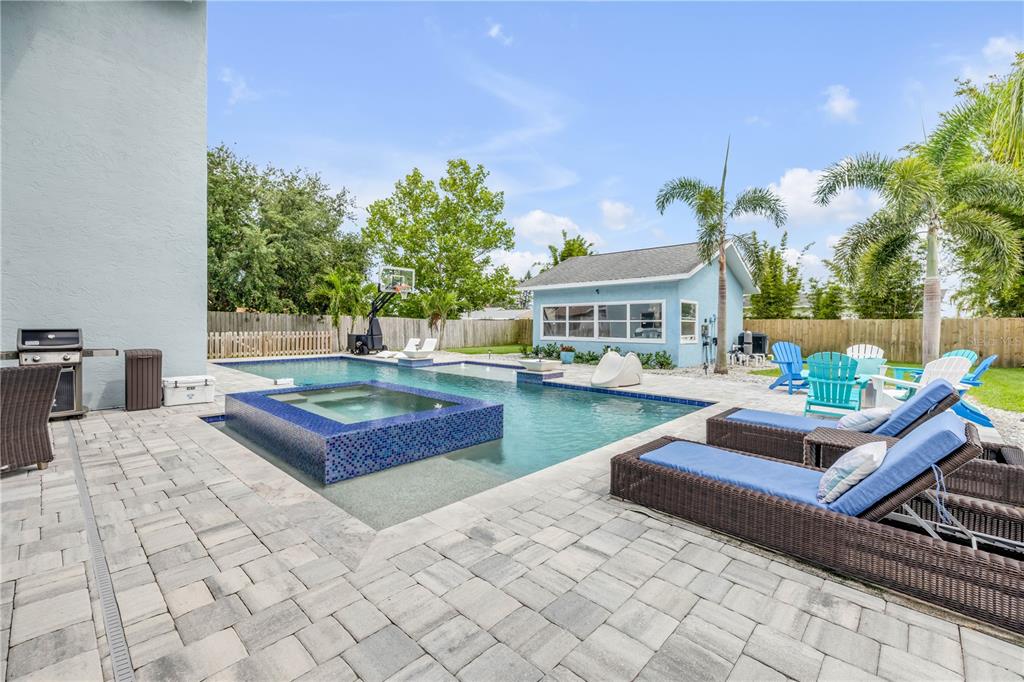 A backyard features a swimming pool with an attached spa, lounge chairs, and a small shed — 90 CUNNINGHAM DRIVE, NEW SMYRNA BEACH, FL
