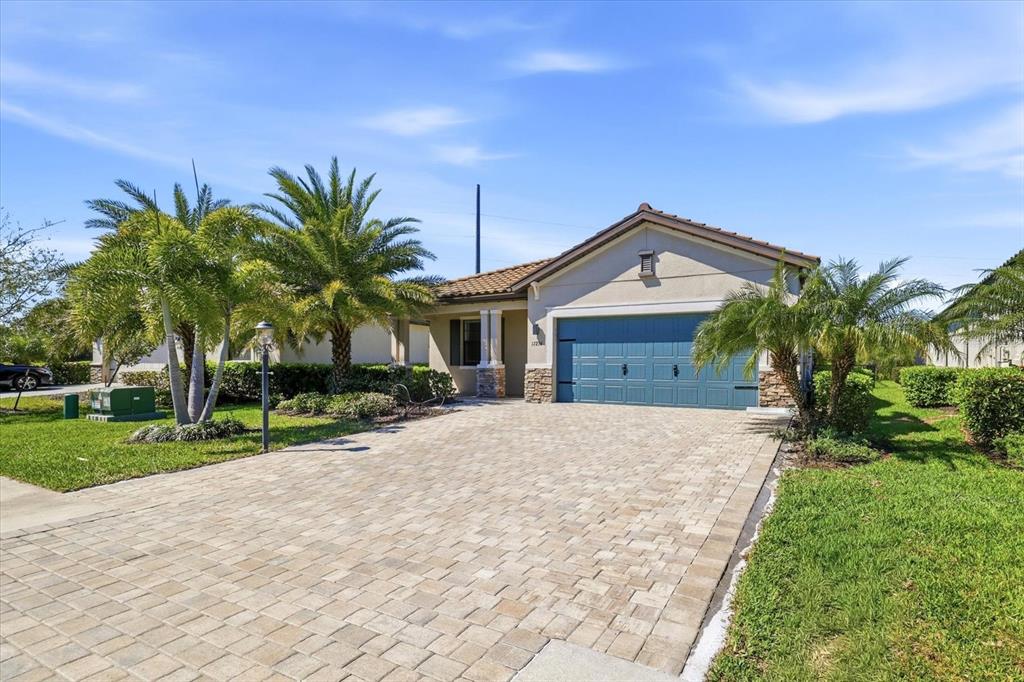 A single-story house with a blue garage door, stone accents, and palm trees — 17234 BLUE RIDGE PLACE, BRADENTON, FL