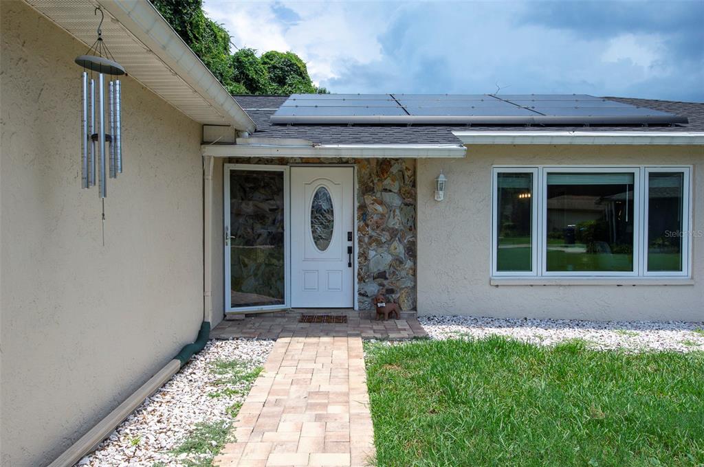 The exterior of a house features a stone-accented entryway, a white front door, and solar panels — 11329 110TH COURT, LARGO, FL