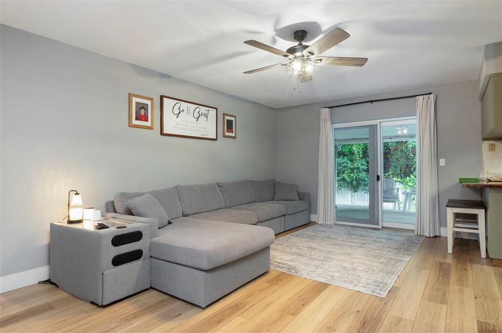 A living room features a gray sectional sofa, light wood flooring, and sliding glass doors — 11329 110TH COURT, LARGO, FL