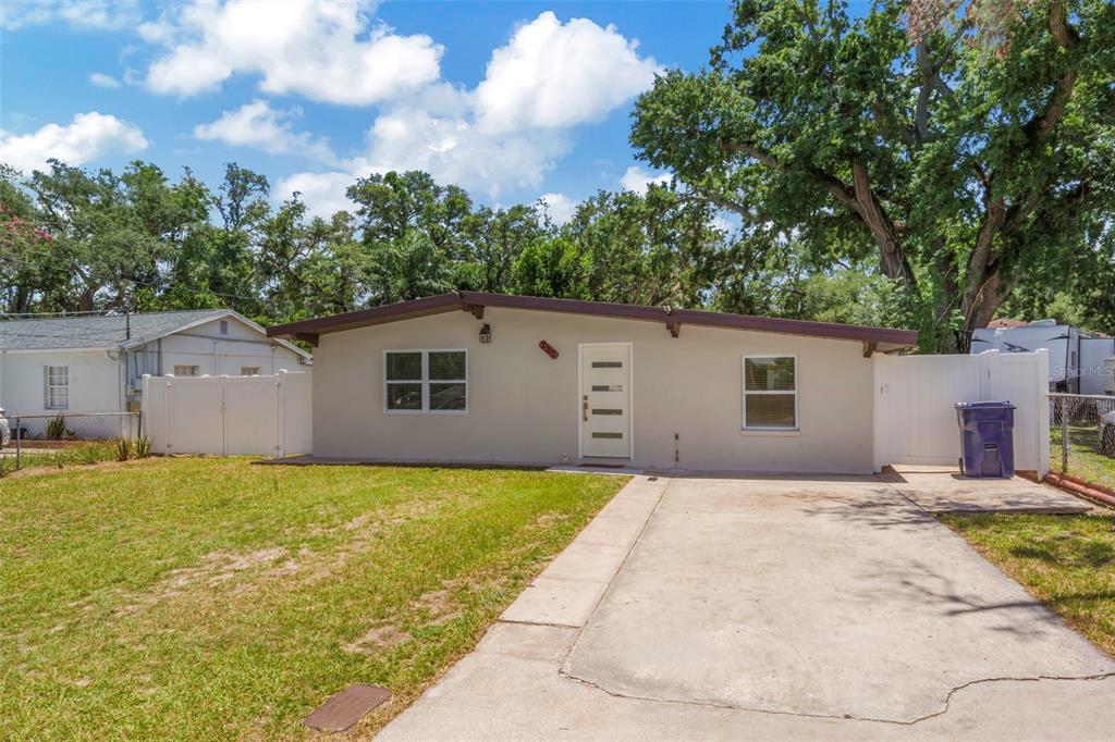 A single-story house with a beige exterior, a concrete driveway, and a white front door — 2112 W IDLEWILD AVENUE, TAMPA, FL