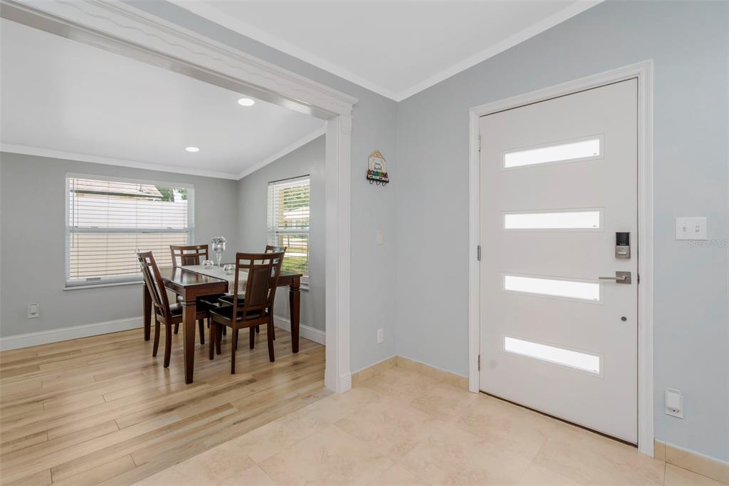 A foyer with tile flooring leads into a dining room featuring wood-look floors and windows — 2112 W IDLEWILD AVENUE, TAMPA, FL